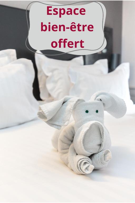 an elephant stuffed animal sitting on a bed at La Table de Gustave Hôtel Restaurant Espace Bien-Être in Ornans