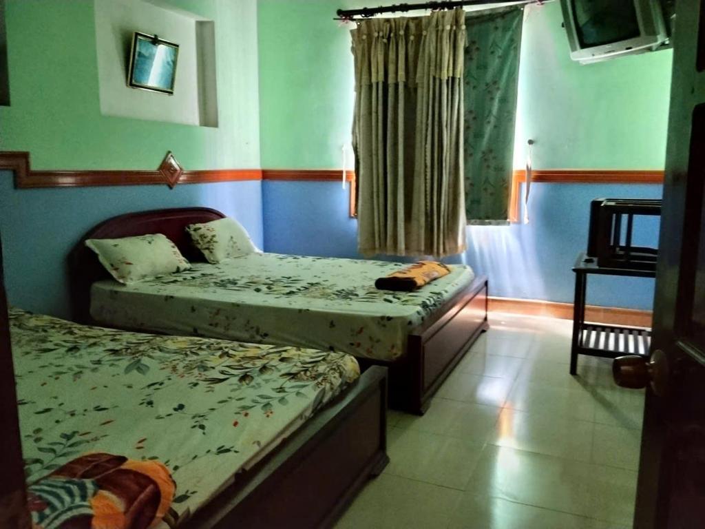 two twin beds in a room with a window at Hotel Khúc Thuỵ Du in Hiệp Hòa