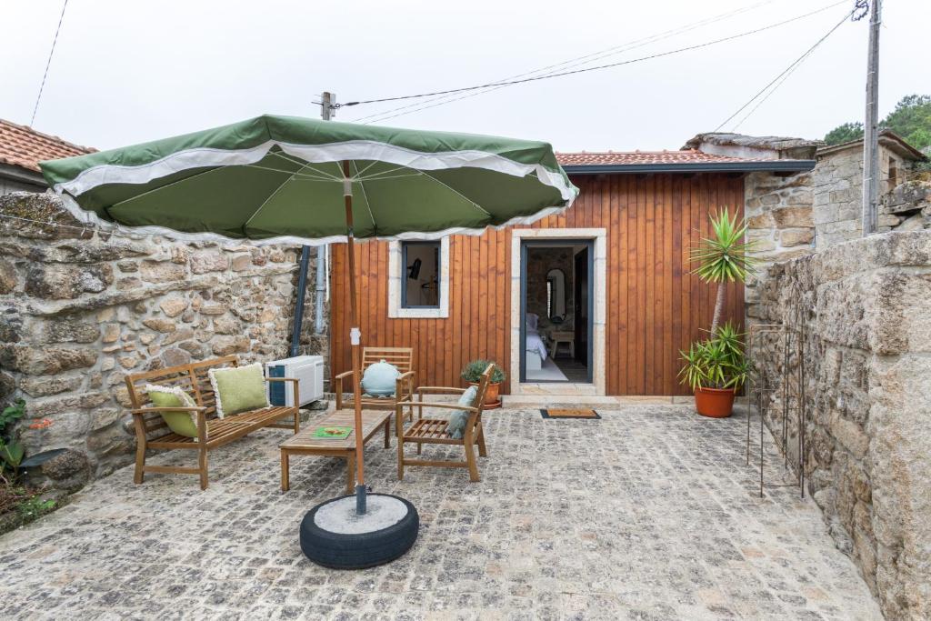 a patio with a table and a green umbrella at Casa do Monte - Monção in Poças do Monte