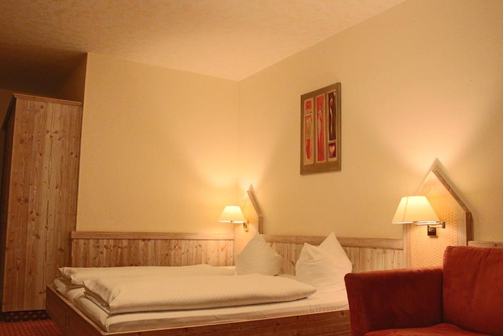 Cama en habitación con 2 lámparas y sofá en Central-Hotel en Winterberg