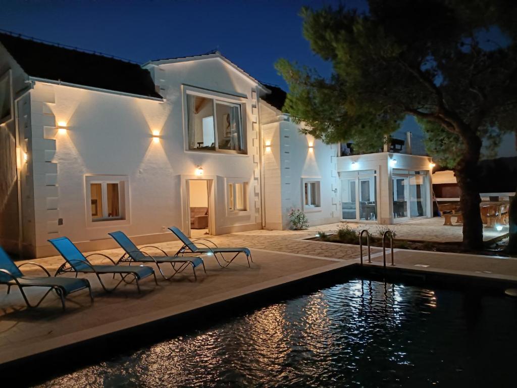 a villa with a swimming pool at night at Vila Nikola in Pučišća
