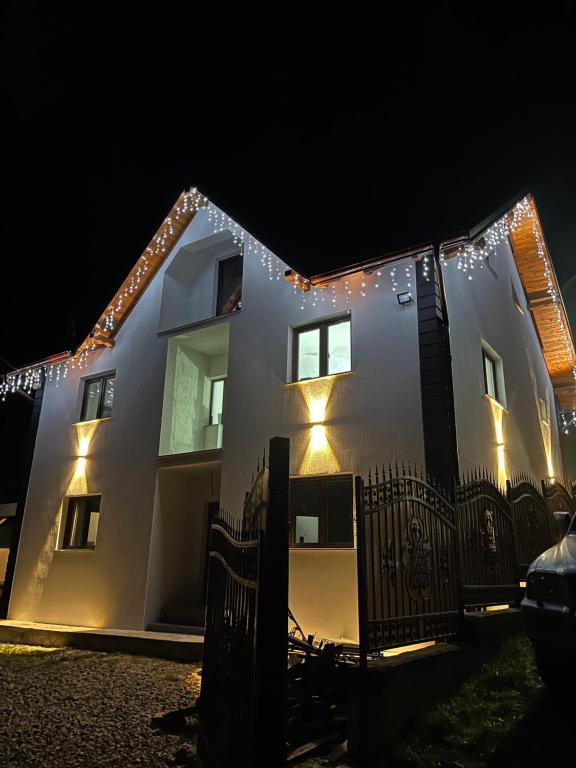 a white house with lights on it at night at Căsuța Găvruj in Săcel