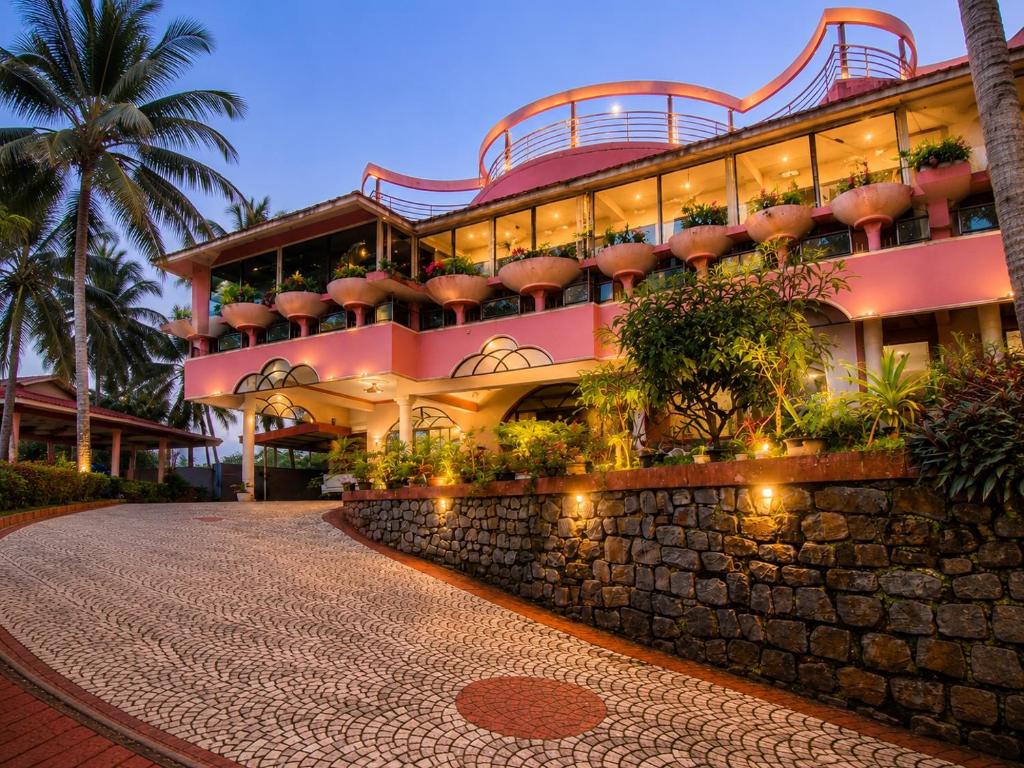 a large pink building with a stone wall at Rose Villa Kovalam in Kovalam