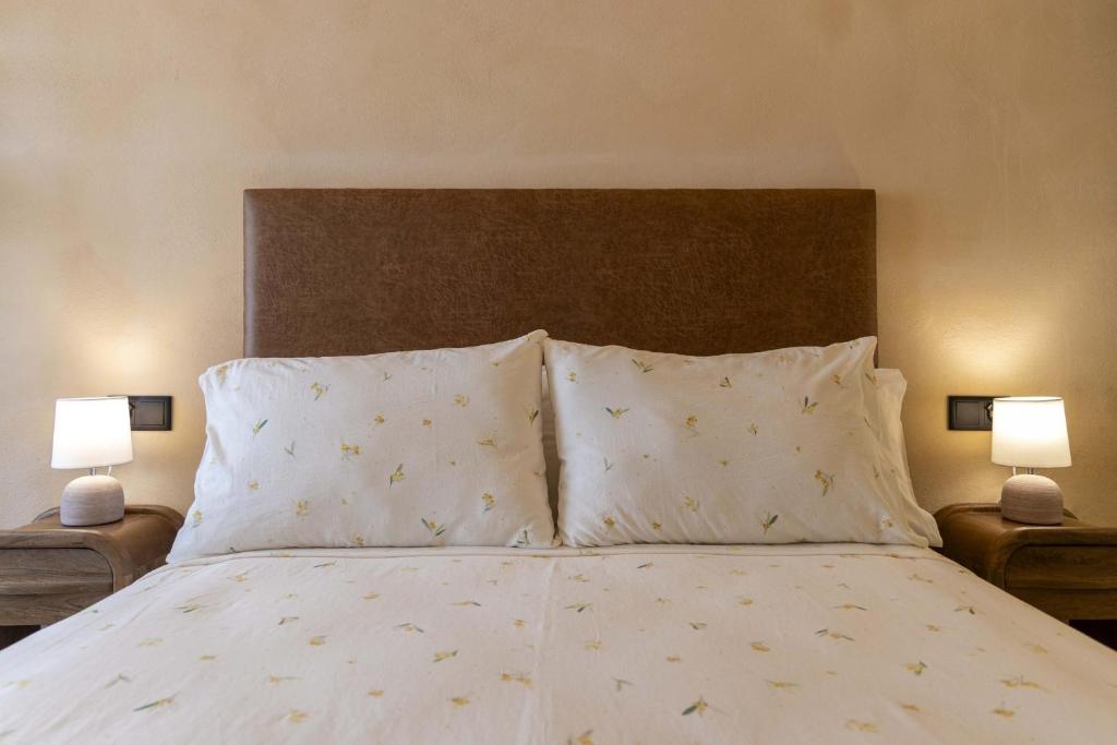 a bedroom with a bed with two pillows and two lamps at Artilles Suites in Peniscola