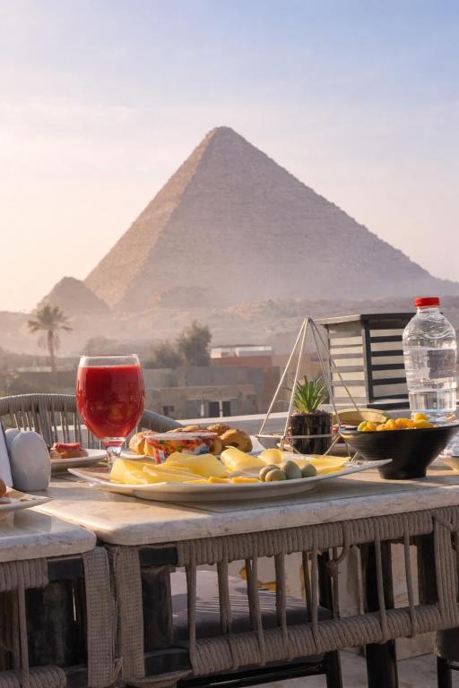 a table with a plate of food and a pyramid at pyramids palace view With Rooftop Access in Cairo