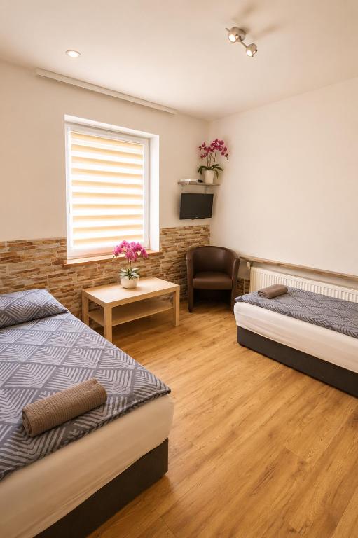 a bedroom with two beds and a chair and a window at Pokoje Bielsko in Bielsko-Biała