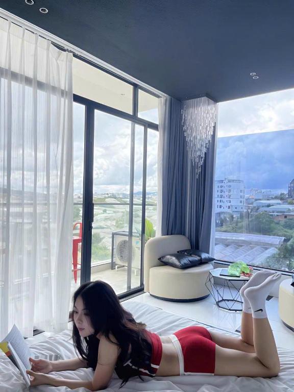 a woman laying on a bed reading a book at Lyn's Hotel Da Lat in Da Lat