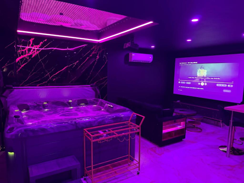 a room with a bed and a tv with purple lights at La Suite Prestige in Saint-Quentin