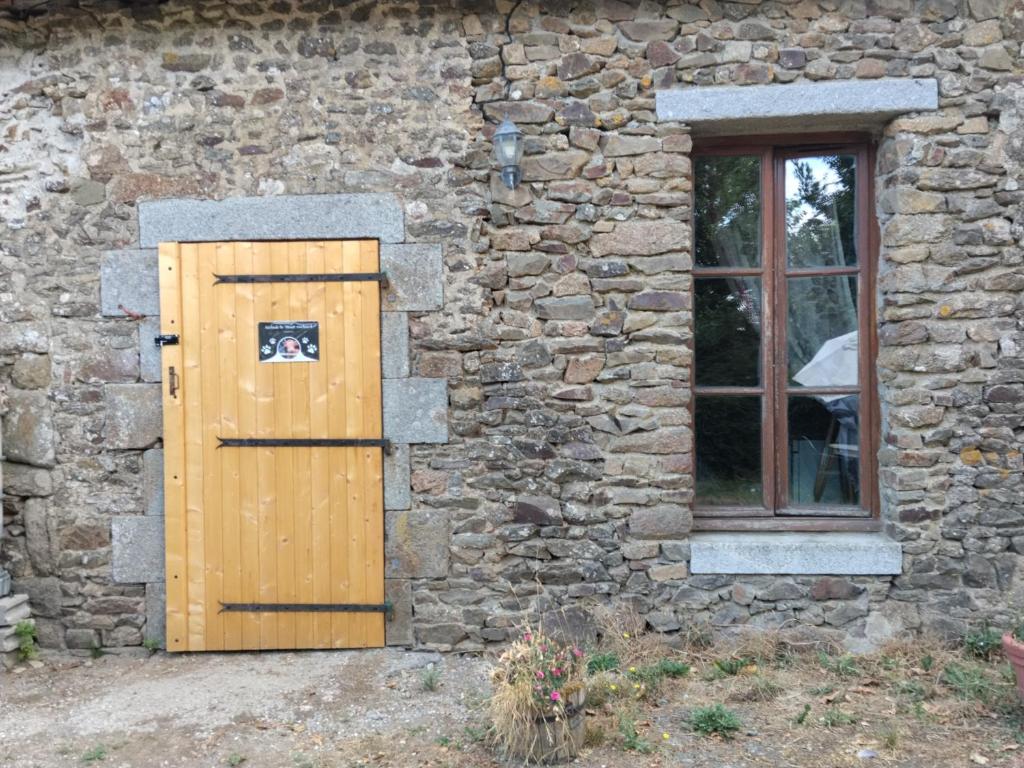 a stone building with a wooden door and a window at Le Mont Rochard in Sainte-Gemmes-le-Robert
