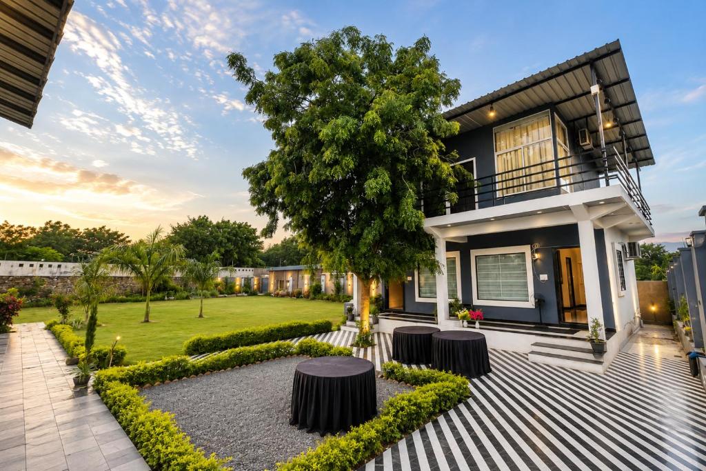 a house with a courtyard with a tree at Atithi Farms - 4 BHK Farm Villa with Private Pool in Thūr