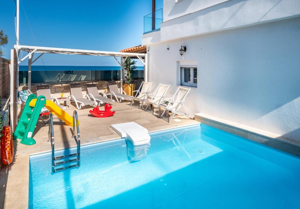 a swimming pool with chairs and a slide next to a house at Marelia Memories villa in Skaleta