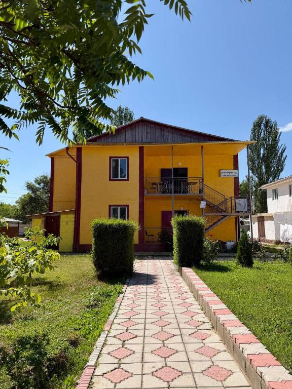 a yellow house with a pathway in front of it at Jibek Murok in Bosteri