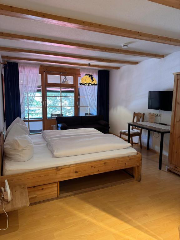 a bedroom with a large bed in a room with a desk at Hotel Maien in Todtmoos in Todtmoos
