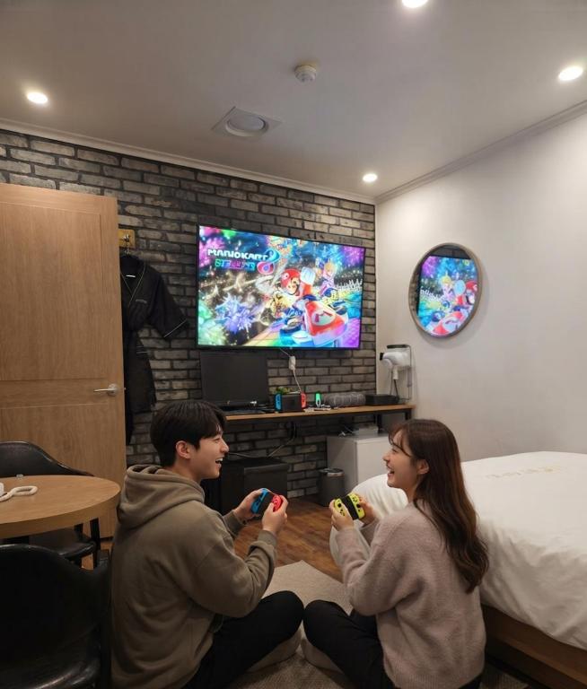 two people sitting on the floor playing a video game at 힐링모텔 in Inch'ŏn-yŏk