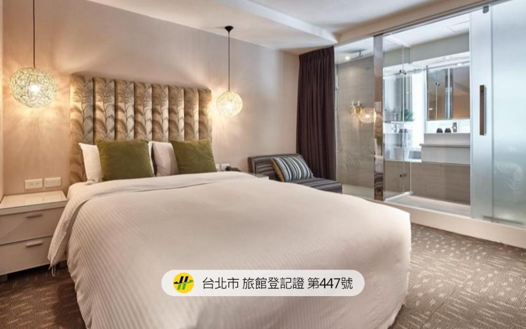 a bedroom with a large white bed and a bathroom at Via Loft Hotel in Taipei