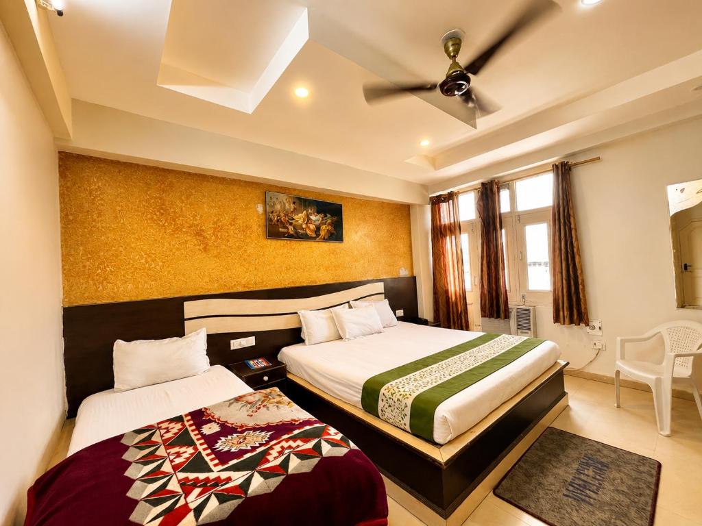 a hotel room with two beds and a ceiling fan at Hotel SVD HARIDWAR in Haridwār