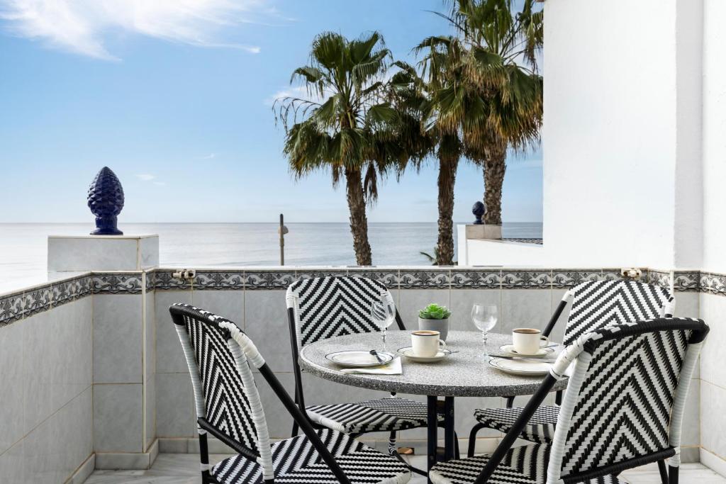 a table and chairs on a balcony with a view of the ocean at Beachfront Apt Torrox Costa in Torrox
