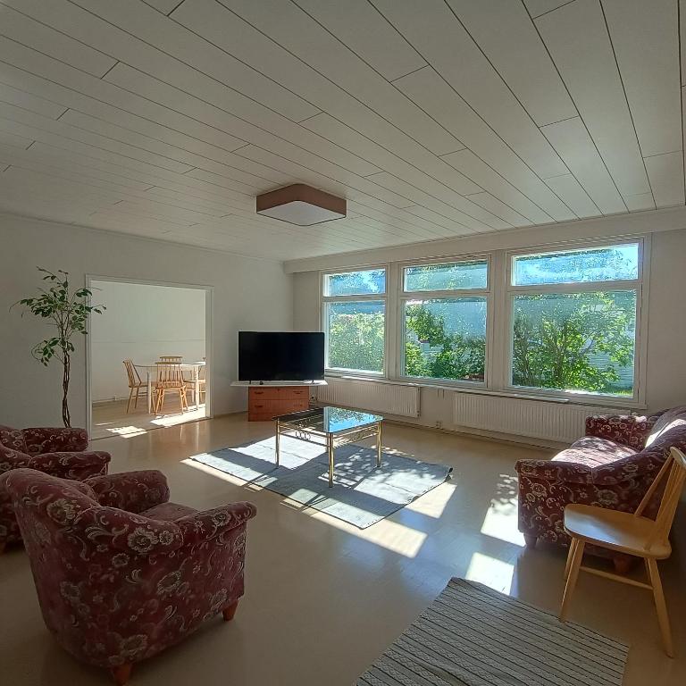 a living room with chairs and a tv and windows at Villa Aspen in Kokkola