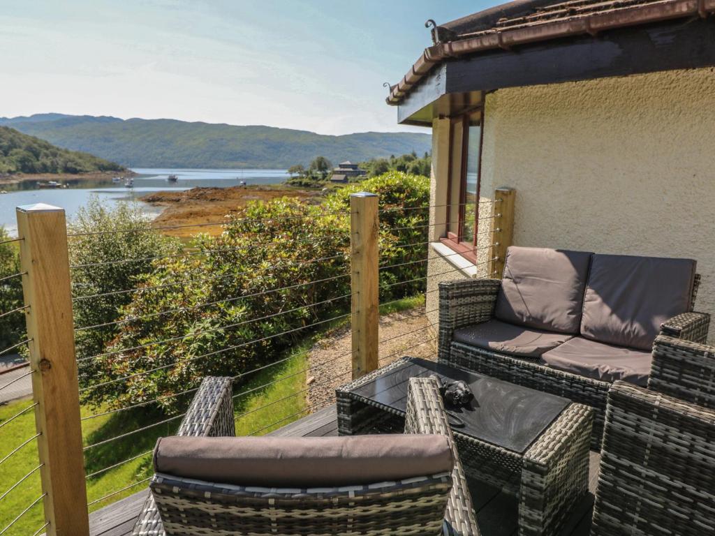 a patio with a table and chairs on a balcony at Allt An Dorran in Acharacle