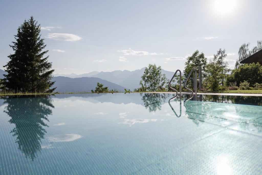 a swimming pool with mountains in the background at Hotel Oberwirt in Verano
