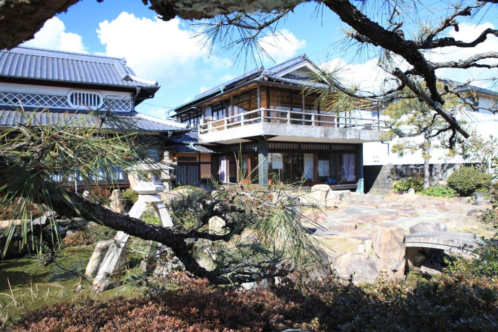 a house on a hill with a tree at Okayama Hostel Igusa in Hayashima