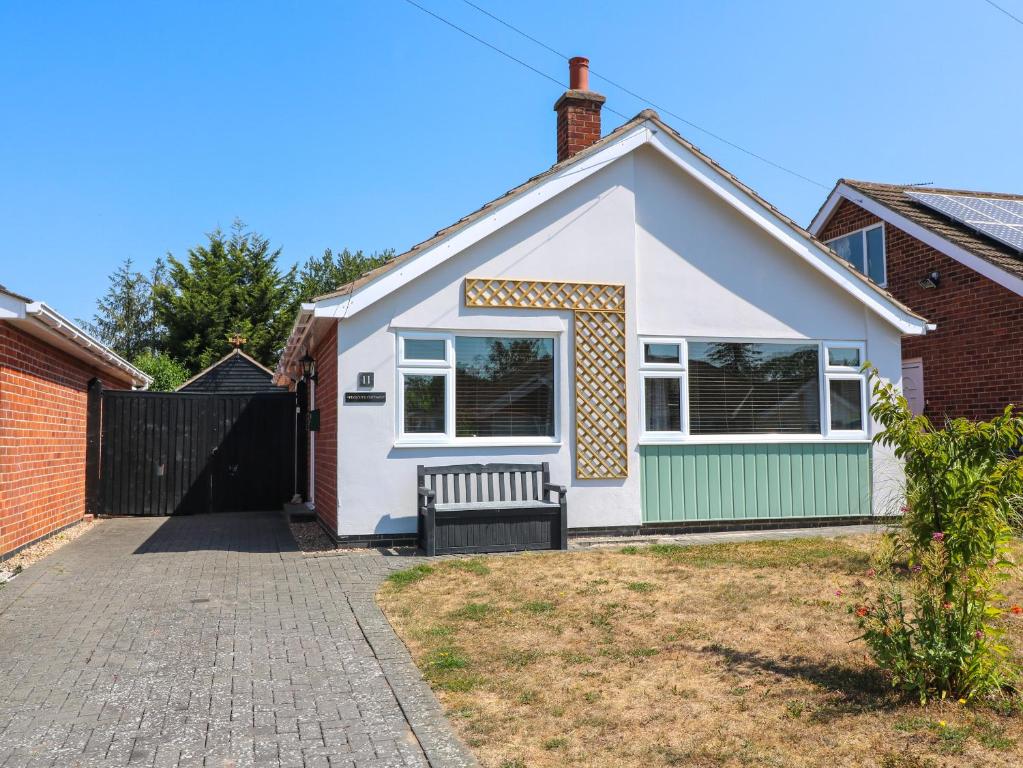 a white house with a bench in the driveway at Pinecote Cottage in Nottingham