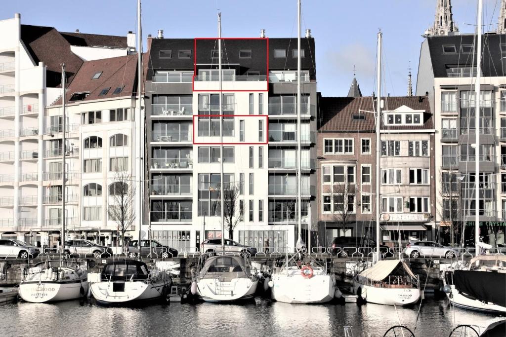 a group of boats docked in a marina with buildings at Whaaw Oostende in Ostend
