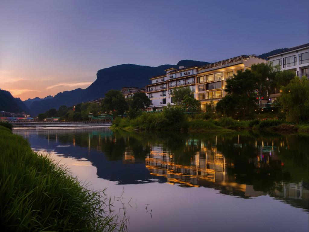 a view of a river with houses and mountains at Zhangjiajie National Park East Gate Happy Hotel-River View&City Center&Book Tickets&English Speaking&Free Laundry in Hanqiyu
