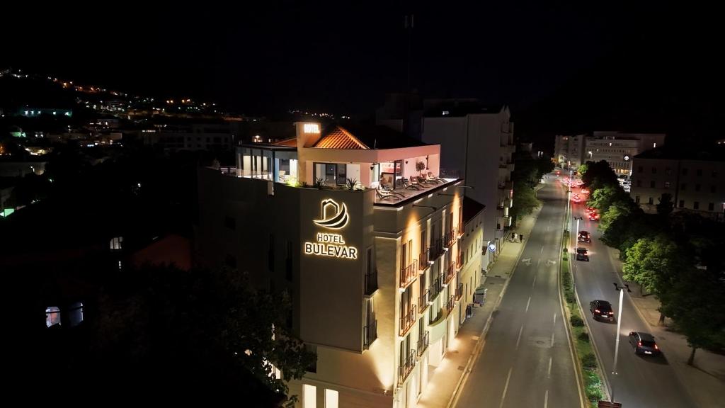 a building with a sign on the side of a street at Hotel Bulevar Mostar in Mostar