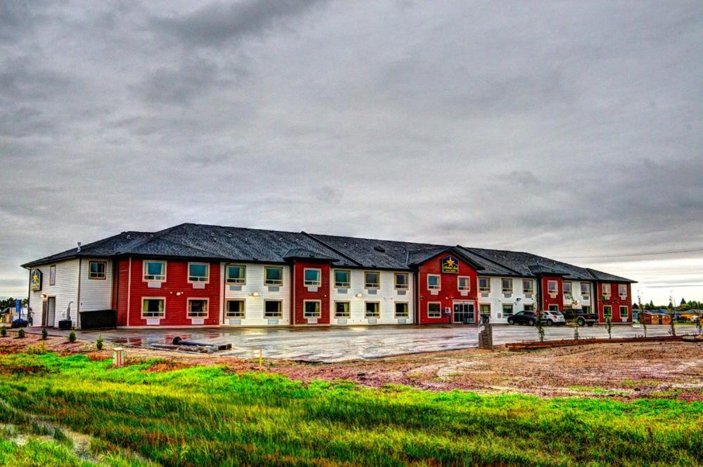 a large red and white building in a field at Western Star Inn & Suites Esterhazy in Esterhazy