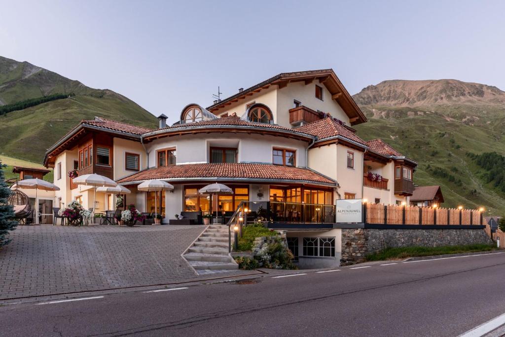 a large house on the side of a mountain at Hotel Alpenjuwel in Melago