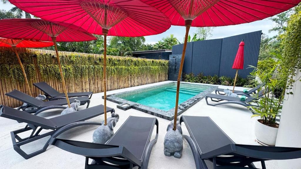 a patio with umbrellas and chairs and a swimming pool at Aranya Bliss Villa 105 in Ban Madua Wan