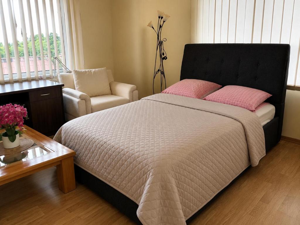 a bedroom with a bed with pink pillows and a chair at Venta City Apartment in Venta