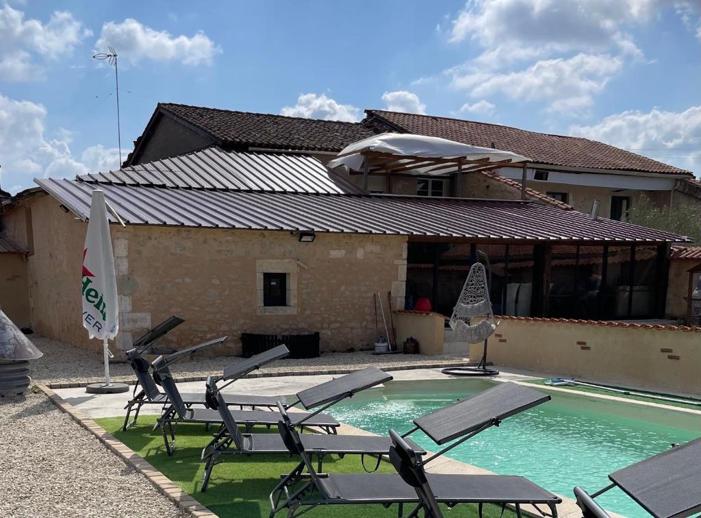 a house with a swimming pool with chairs and a house at L’alambic in Guizengeard