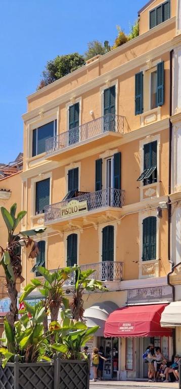 a large yellow building with people sitting outside of it at Pisolo Resort in Sanremo