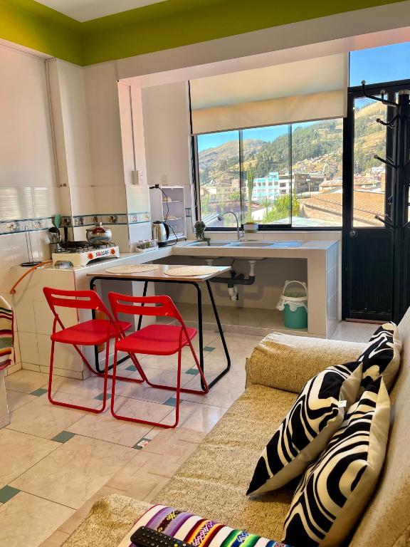 a kitchen with a table and two red chairs in a room at Alojamiento en SICUANI in Sicuani