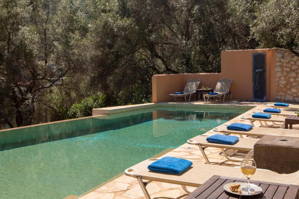 a pool with chaise lounge chairs and a swimming pool at Villa Amoudia - Luxury Villa right on the beach with Private Pool in Sivota