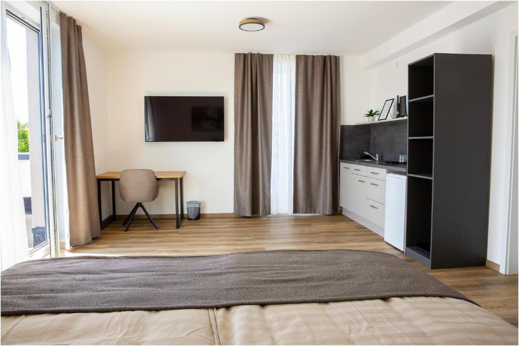 a bedroom with a bed and a desk and a tv at Pension Malia in Fronhausen