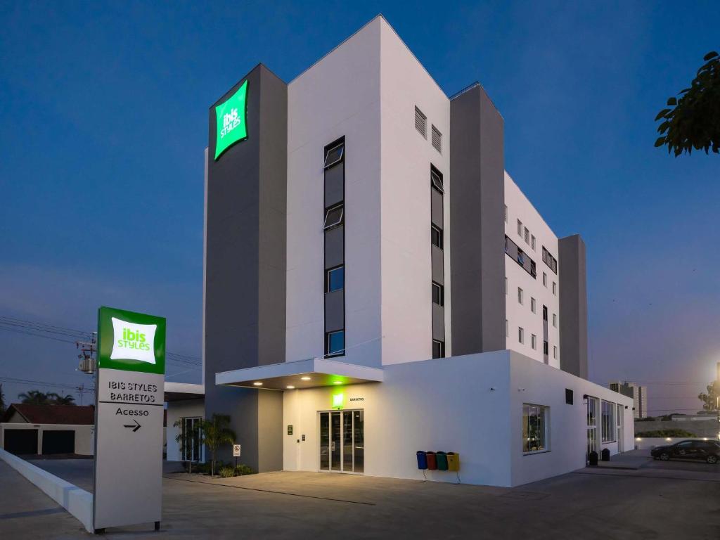 a large white building with a green sign on it at Ibis Styles Barretos in Barretos