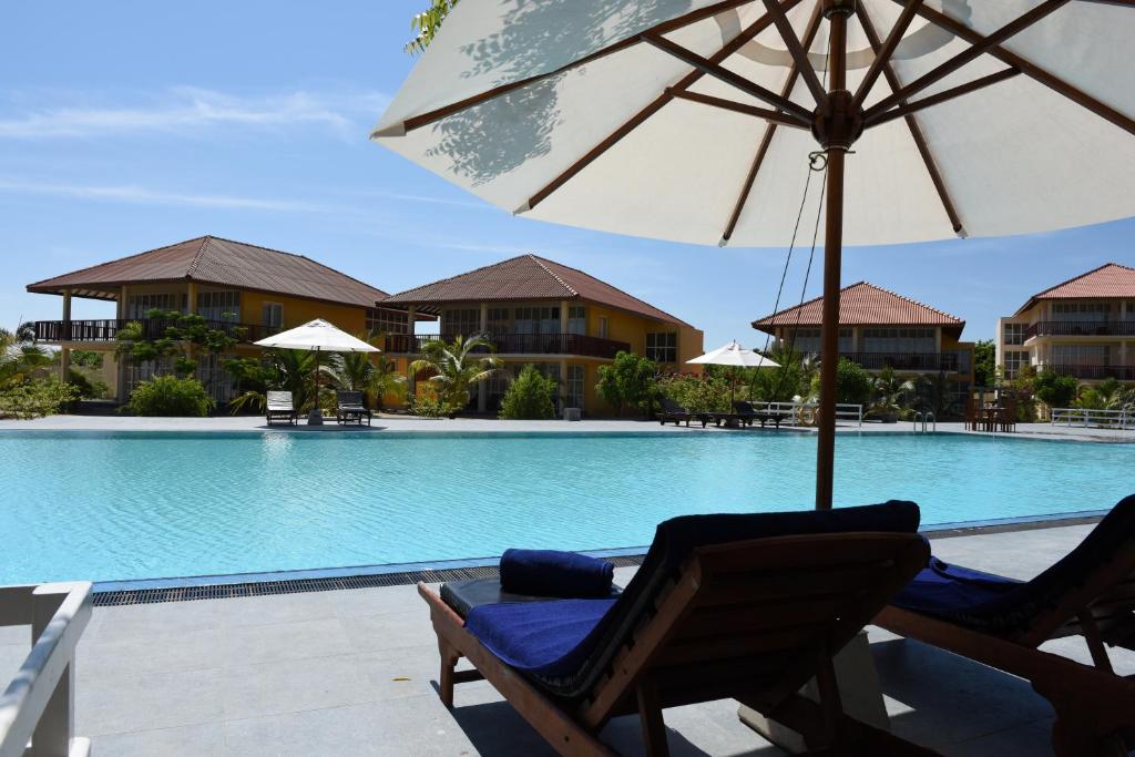 a chair with an umbrella next to a swimming pool at Passi Villa in Pasikuda