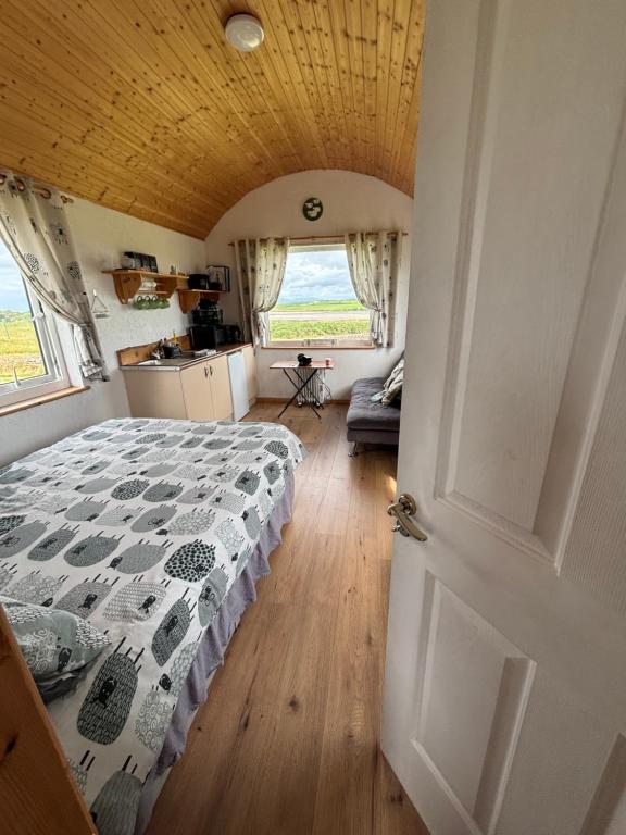 a bedroom with a bed with a comforter on it at The Snuggly Sheep Farm Stay Shepherd Hut in Ballyshannon
