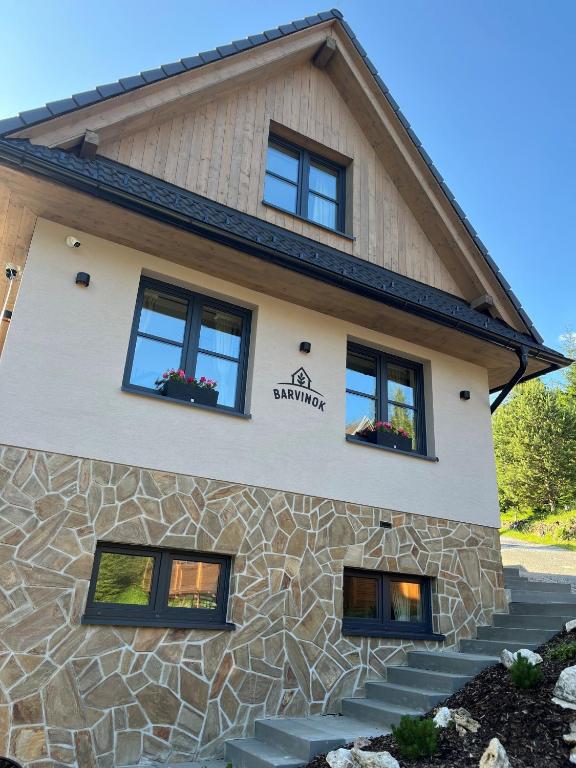 a house with black windows and a stone wall at Chata Barvinok in Litmanová