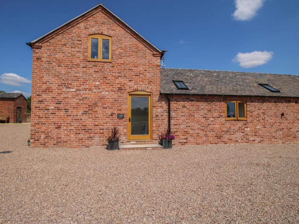 a brick house with a yellow door in a gravel yard at Chestnut Barn in Shrewsbury