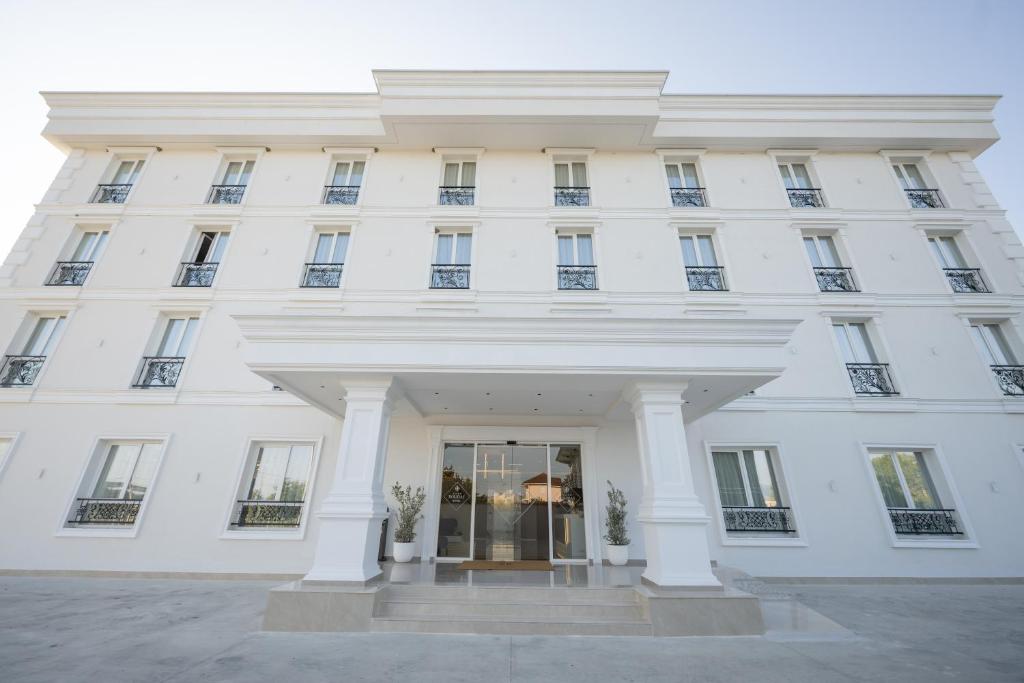 a large white building with a revolving door at Hotel By Holiday in Rinas