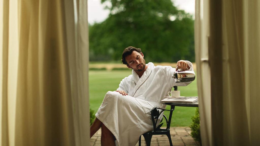a man in a robe is sitting at a table with a tea kettle at Rockliffe in Darlington