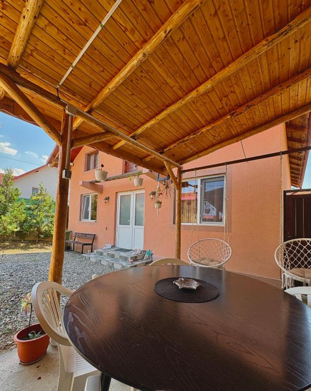 a wooden table and chairs under a wooden pergola at Casa Iulia in Eşelniţa