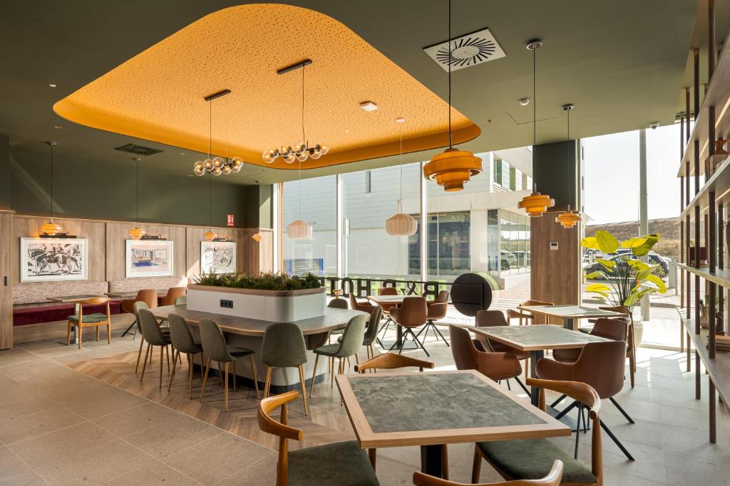 a restaurant with tables and chairs and windows at B&B HOTEL Murcia Thader in Churra