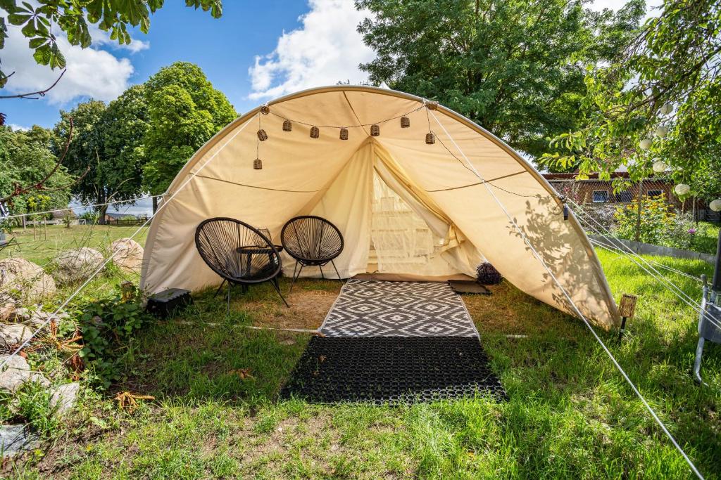 a tent with two chairs in the grass at Tipi Jurte Zelt in der Seenplatte in Carpin