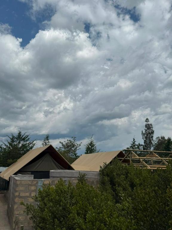 a building under a cloudy sky with a roof at Serenity Glamping By Rafiki in Nanyuki