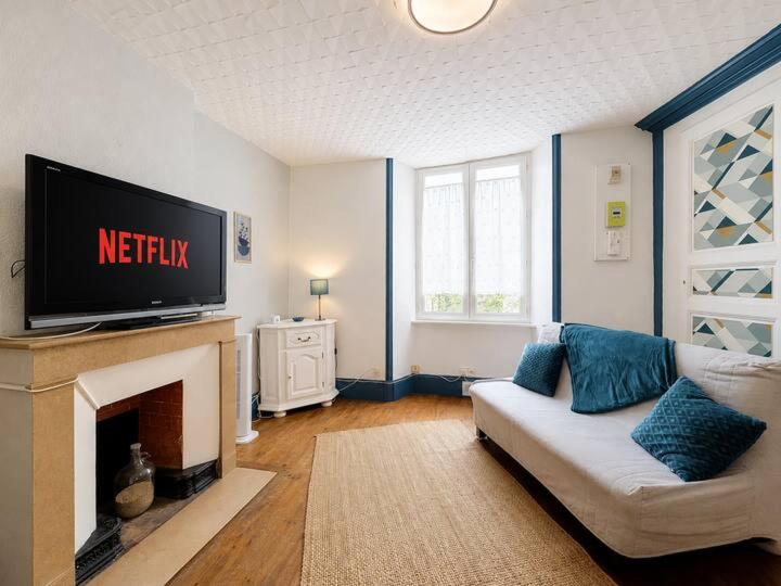 a living room with a white couch and a tv at Azur des jardins in Annonay
